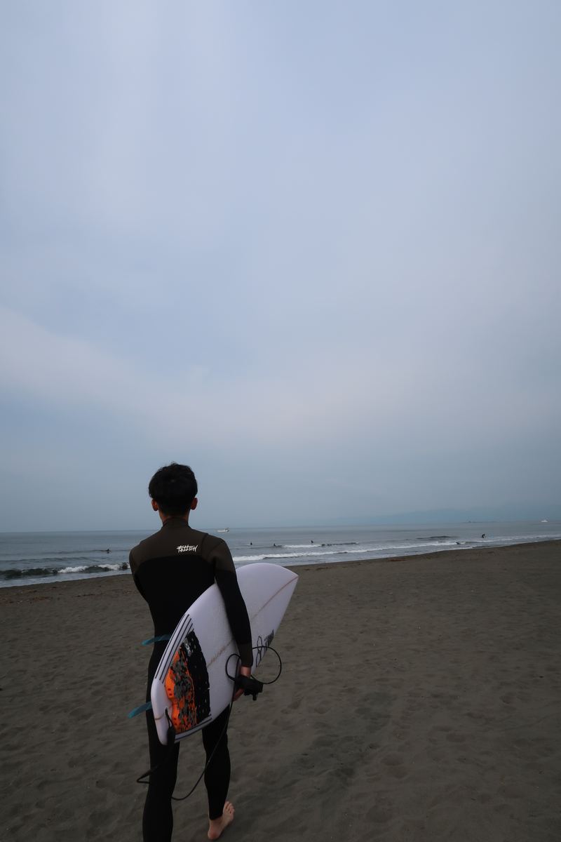 サーフボードを抱えて海に向かう後ろ姿